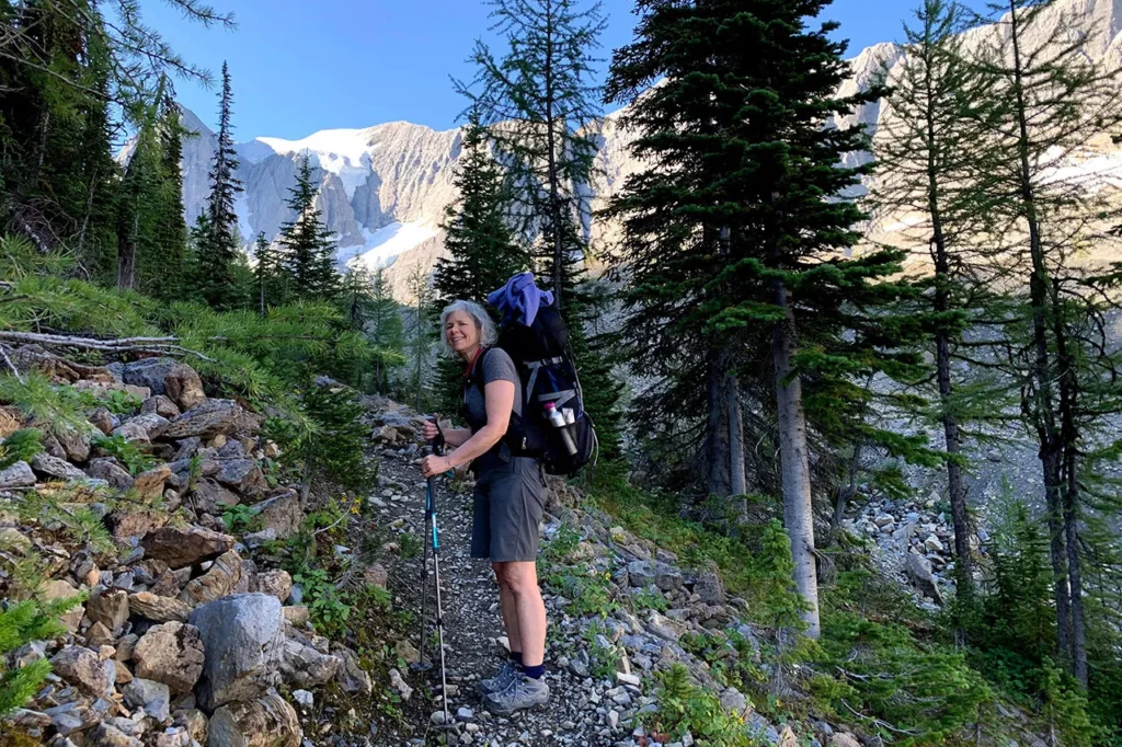 A woman hiking with a backpack on a trail in the mountains.